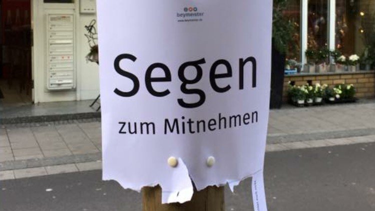 Auf einem Zettel an einem Holzpfahl steht "Segen zum Mitnehmen" Auf einem Zettel an einem Holzpfahl steht "Segen zum Mitnehmen"