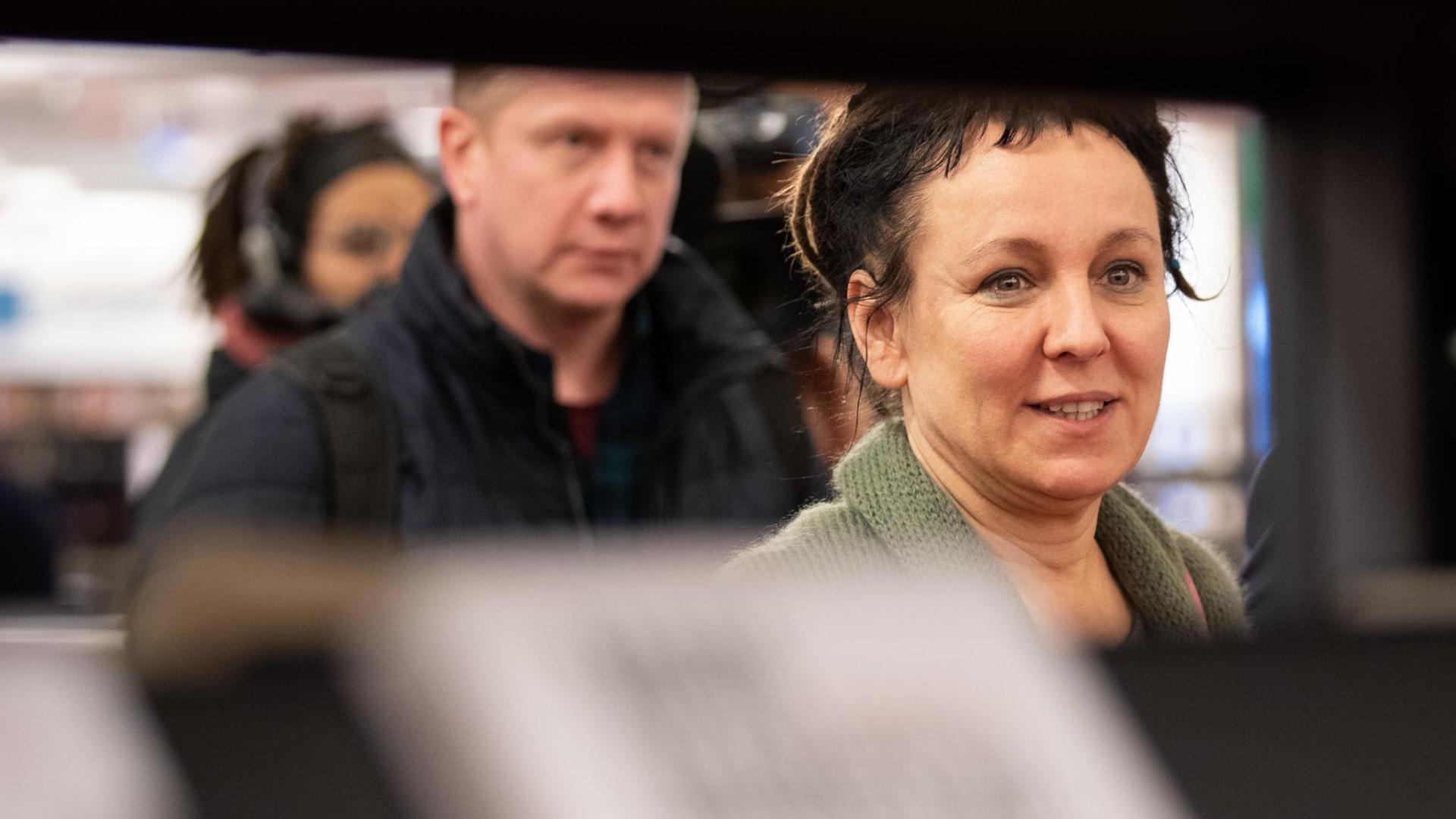 Die polnische Autorin Olga Tokarczuk geht im Vorfeld einer Lesung in Bielefeld durch die Stadtbibliothek vorbei an Bücherregalen. Die polnische Autorin Olga Tokarczuk geht im Vorfeld einer Lesung in Bielefeld durch die Stadtbibliothek vorbei an Bücherregalen.