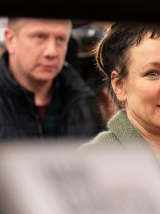 Die polnische Autorin Olga Tokarczuk geht im Vorfeld einer Lesung in Bielefeld durch die Stadtbibliothek vorbei an Bücherregalen.