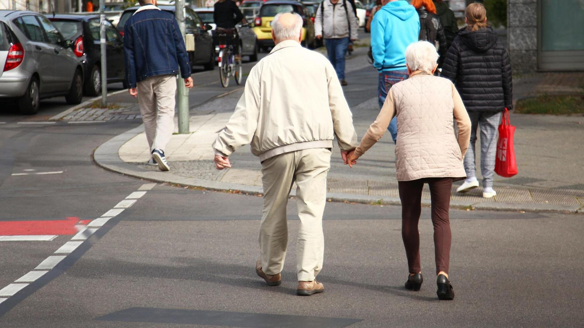 Ein Rentnerpaar überquert eine Straße. Ein Rentnerpaar überquert eine Straße.