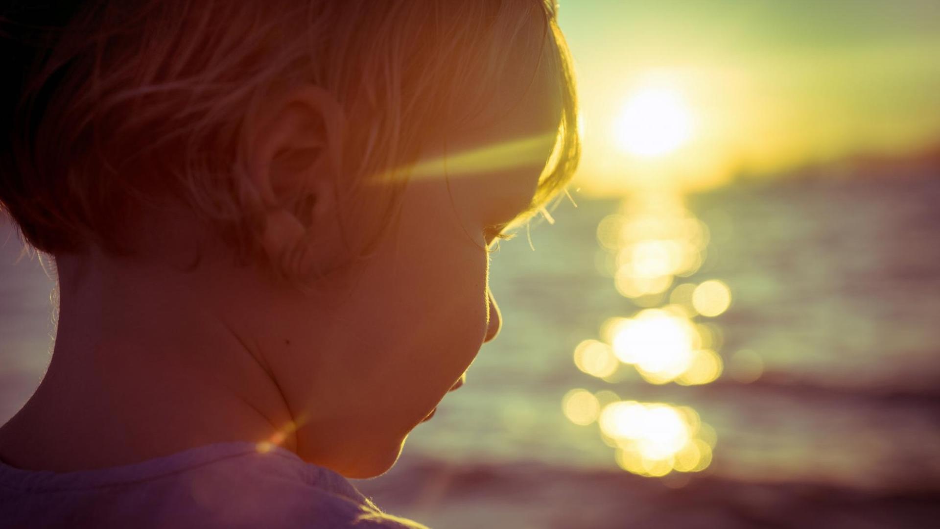 Fotografie eines Kindes am Meer, im Gegenlicht der, am Horizont, untergehenden Sonne. Fotografie eines Kindes am Meer, im Gegenlicht der, am Horizont, untergehenden Sonne.