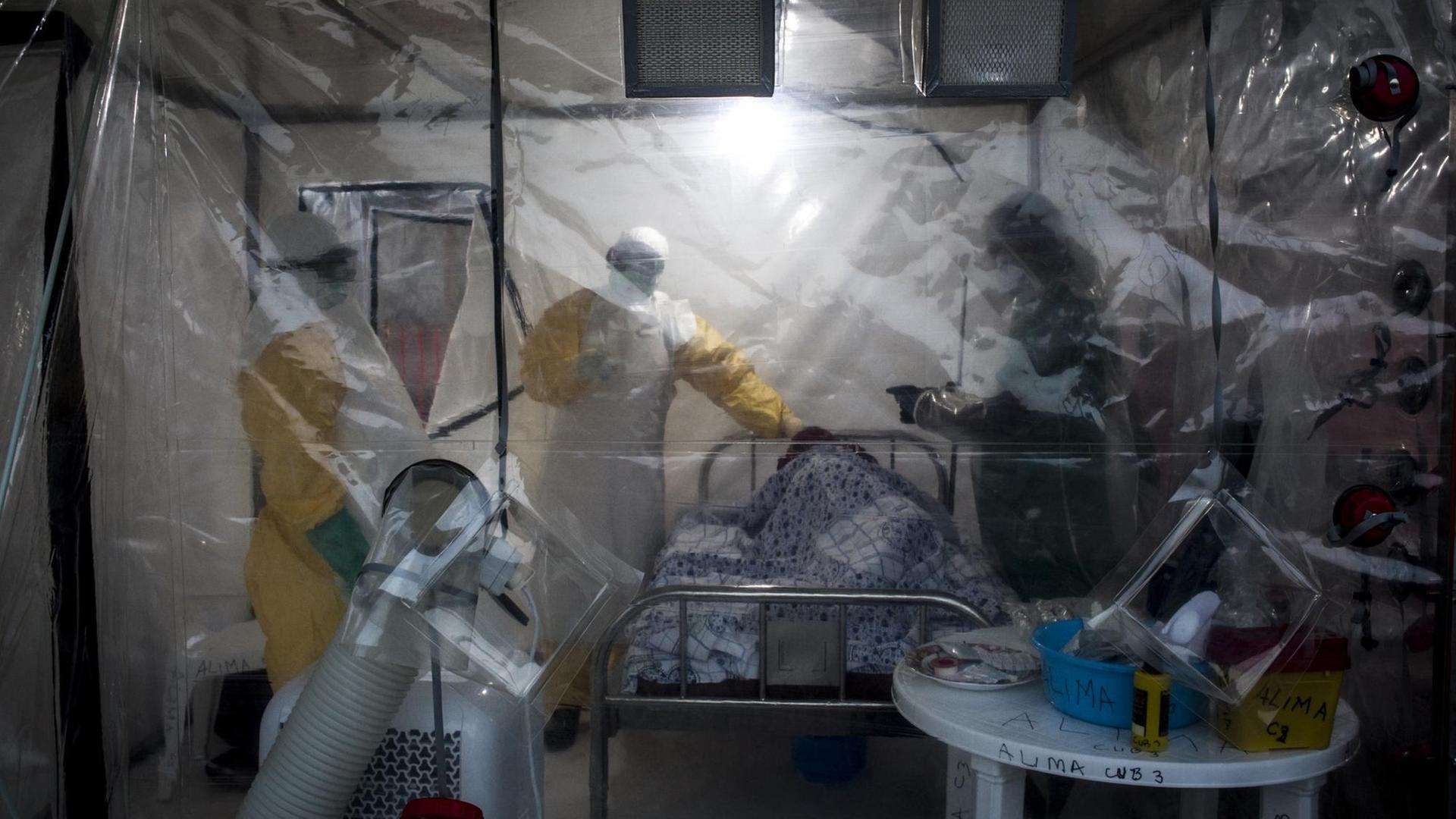 Das Bild zeigt mehrere Pfleger, die in Beni im Kongo einen Ebola-Patienten untersuchen. Dabei kommt erstmals auch ein Zelt mit einem speziellen Sicherheitssystem zum Einsatz. Das Bild zeigt mehrere Pfleger, die in Beni im Kongo einen Ebola-Patienten untersuchen. Dabei kommt erstmals auch ein Zelt mit einem speziellen Sicherheitssystem zum Einsatz.