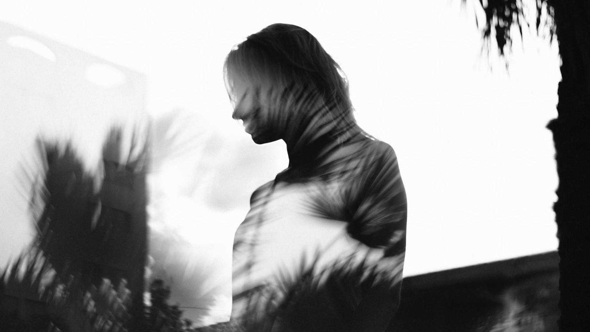Schwarzweißfotografie der Silhouette einer Frau mit iritierenden Lichtspielereien Schwarzweißfotografie der Silhouette einer Frau mit iritierenden Lichtspielereien