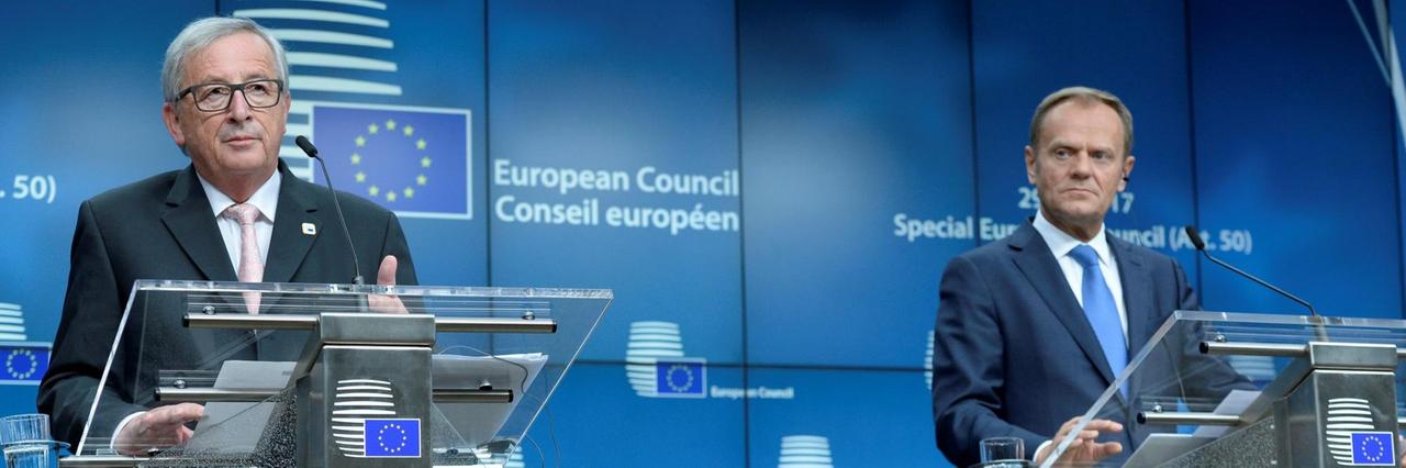 Juncker und Tusk stehen bei der Pressekonferenz nebeneinander auf dem Podium. Juncker und Tusk stehen bei der Pressekonferenz nebeneinander auf dem Podium.