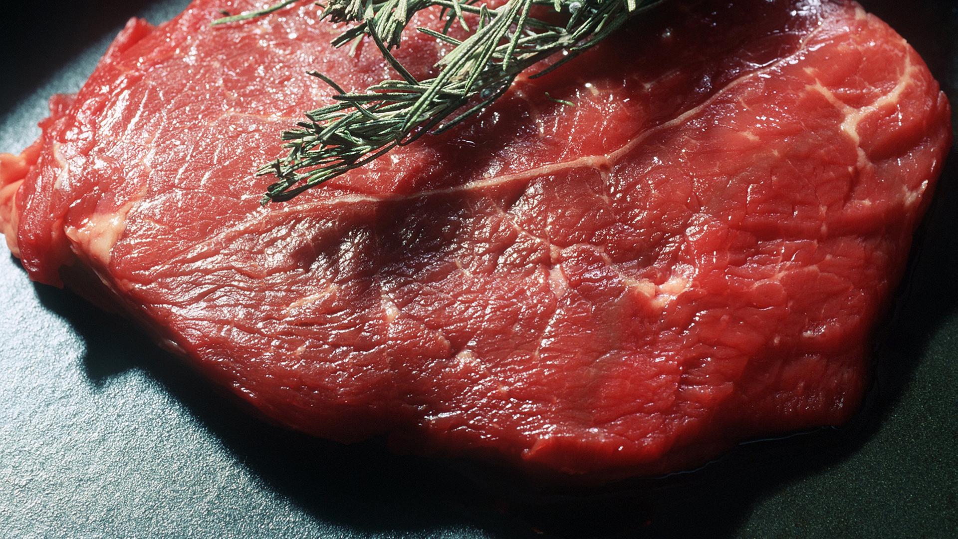 Ein durchwachsenes, rohes Rindersteak, dekoriert mit einem Rosmarinzweig. Ein durchwachsenes, rohes Rindersteak, dekoriert mit einem Rosmarinzweig.