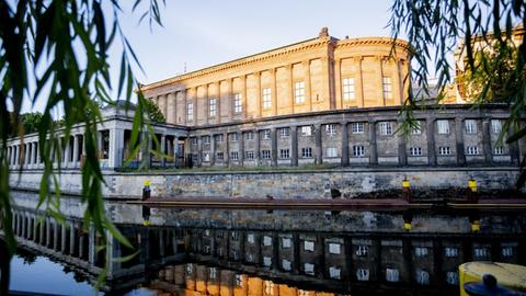 Die Alte Nationalgalerie spiegelt sich im Licht der aufgehenden Sonne in der Spree.