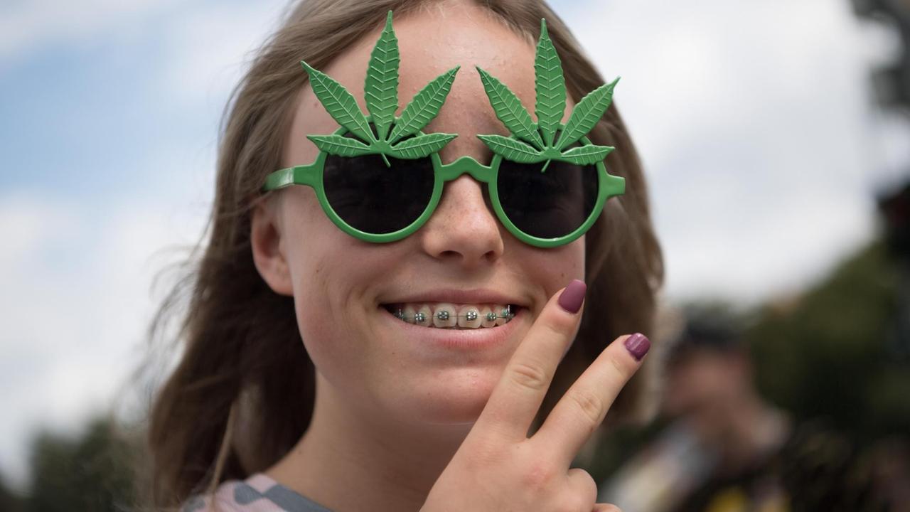 Eine Teilnehmerin der 23. Hanfparade für eine Legalisierung von Cannabis trägt eine Sonnenbrille mit Kunststoff-Hanfblättern.