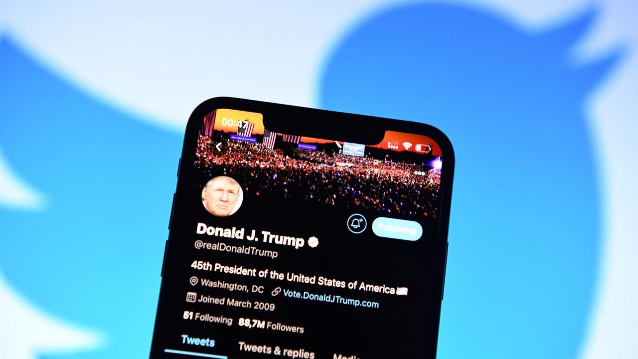 Der Twitter-Account von Donald Trump auf einem Smartphone. Im Hintergrund das Logo von Twitter.