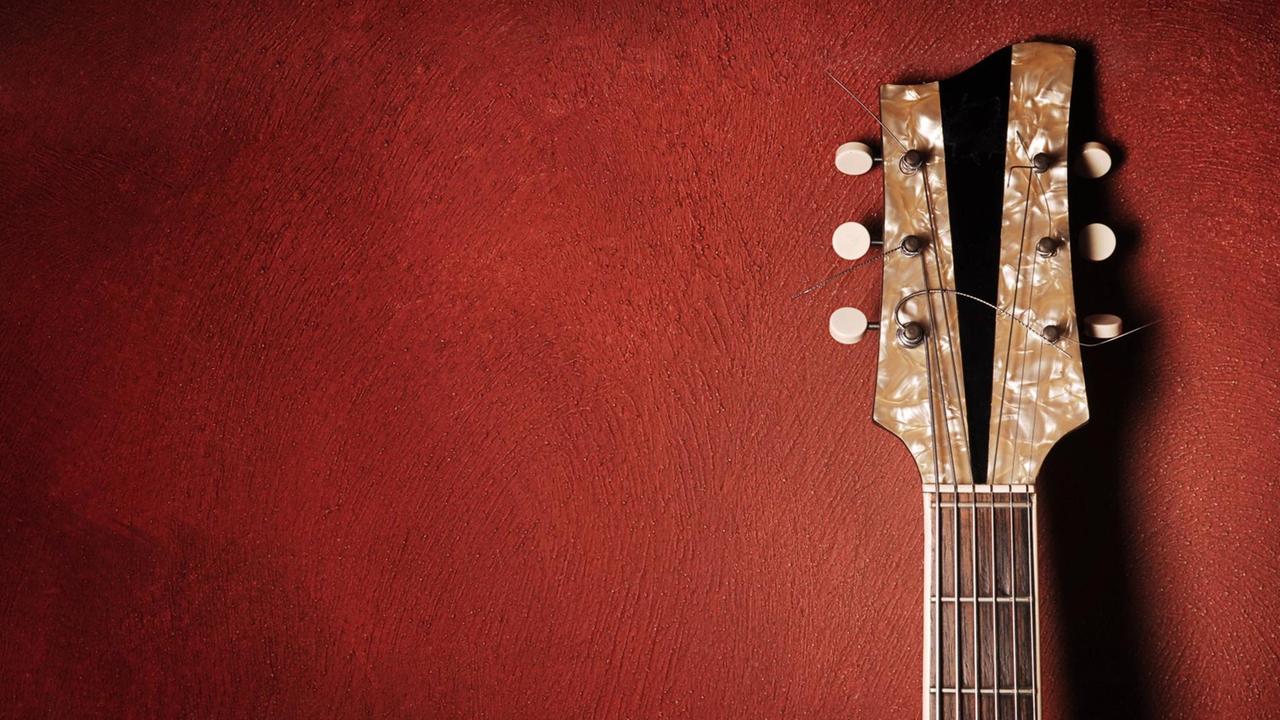 Gitarre lehnt gegen eine rote Wand Gitarre lehnt gegen eine rote Wand