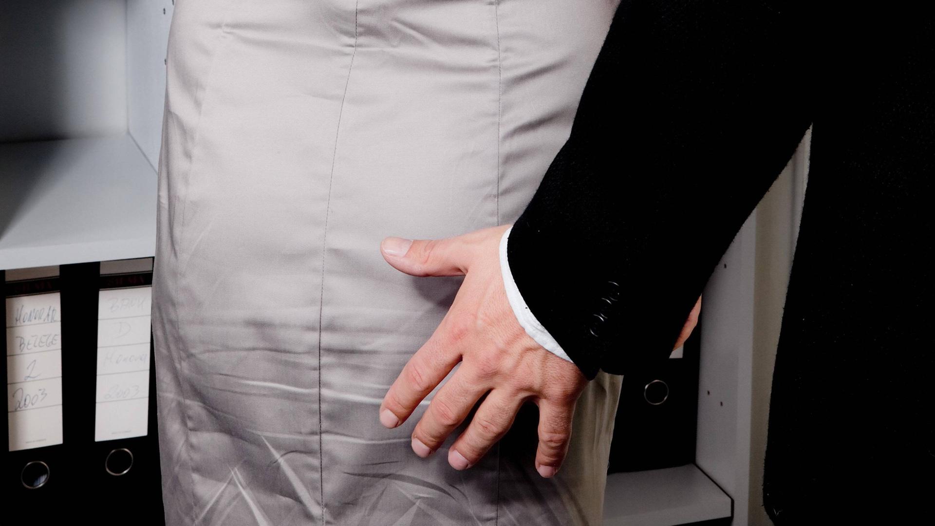 Eine männliche Hand bewegt sich zum Gesäß einer Frau in einem Büro. (Symbolbild) Eine männliche Hand bewegt sich zum Gesäß einer Frau in einem Büro. (Symbolbild)