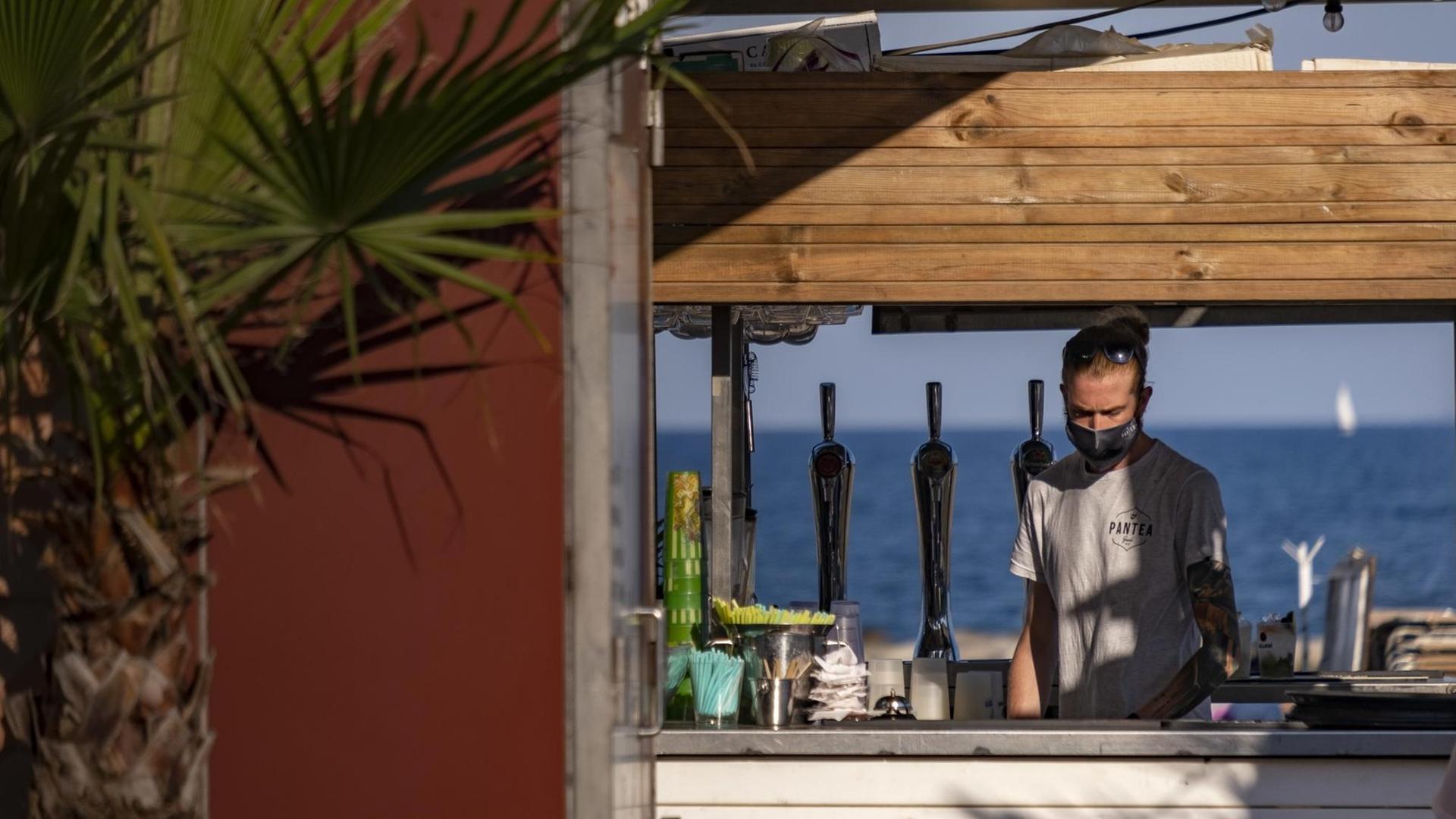 Ein Verkäufer mit Maske in einer Strandbar in Barcelonain Spanien, aufgenommen am 24. Juli 2020 Ein Verkäufer mit Maske in einer Strandbar in Barcelonain Spanien, aufgenommen am 24. Juli 2020