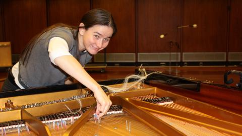 Marina Khorkova präpariert im Kammermusiksaal des Deutschlandfunks die Saiten eines Klavieres mit Metallstiften und Radiergummis