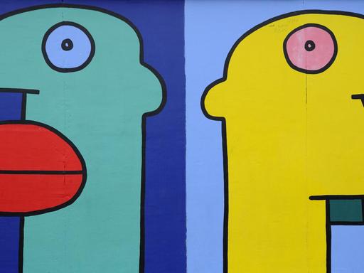 Mauer-Gemälde des Künstlers Thierry Noir. Es zeigt bunte Köpfe im Comicstil auf der Berliner Mauer, East Side Gallery, Berlin.