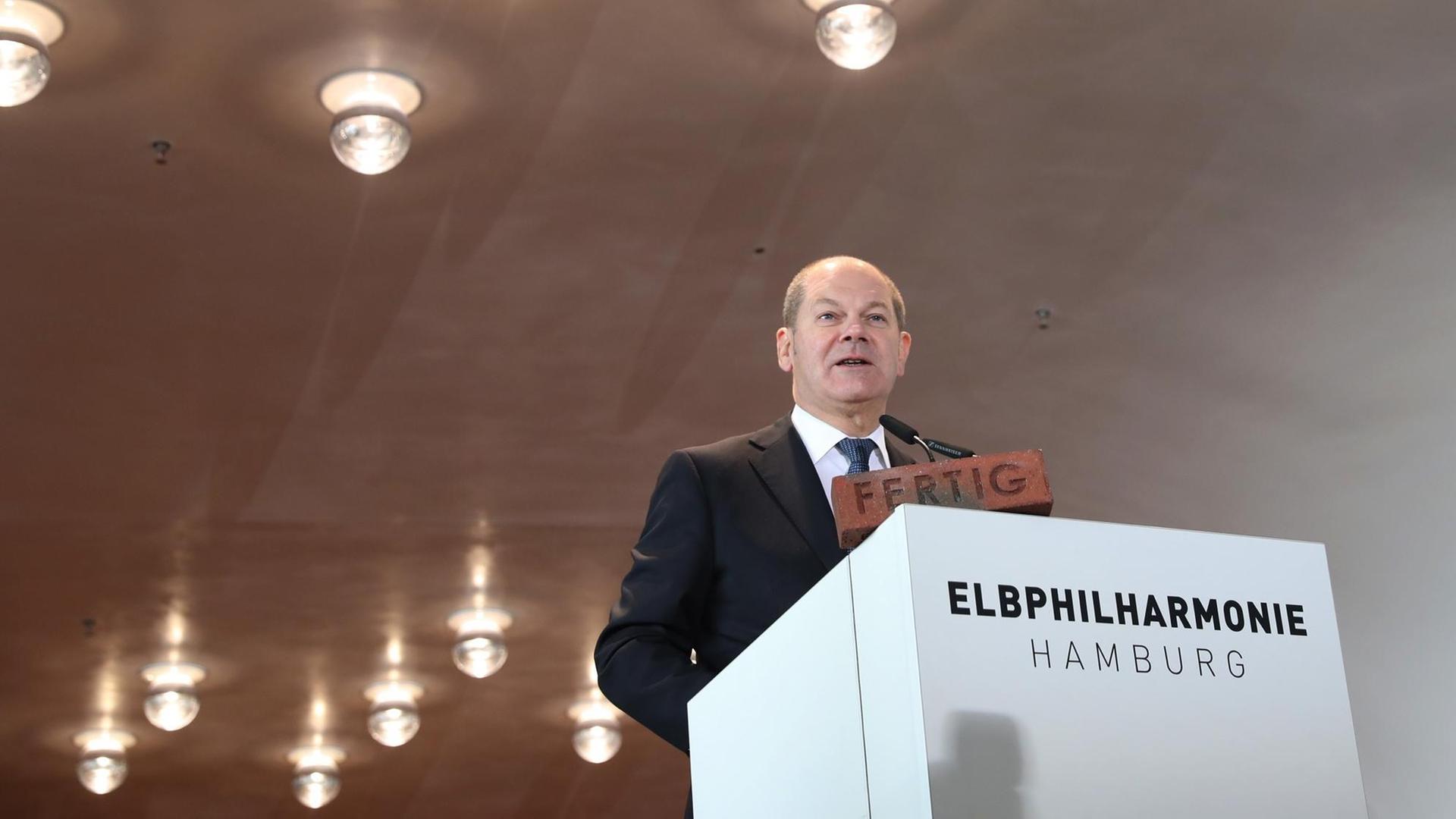 Hamburgs Erster Bürgermeister Olaf Scholz (SPD) steht vor einem weißen Pult mit der Aufschrift "Elbphilharmonie".