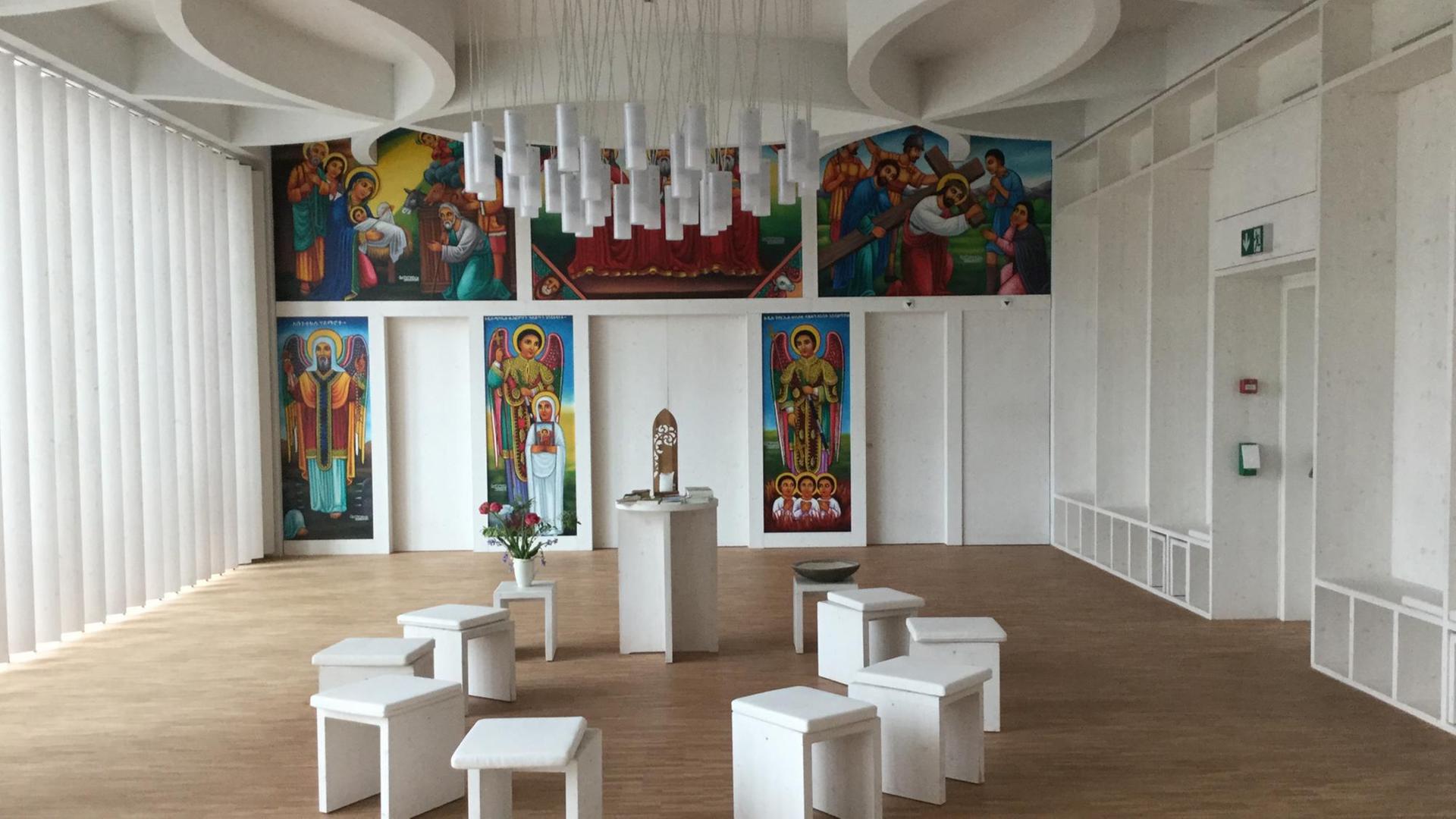 Mehrere weiße Hocker stehen um einen kleinen Tisch, von der Decke hängen weiße Lampen Mehrere weiße Hocker stehen um einen kleinen Tisch, von der Decke hängen weiße Lampen