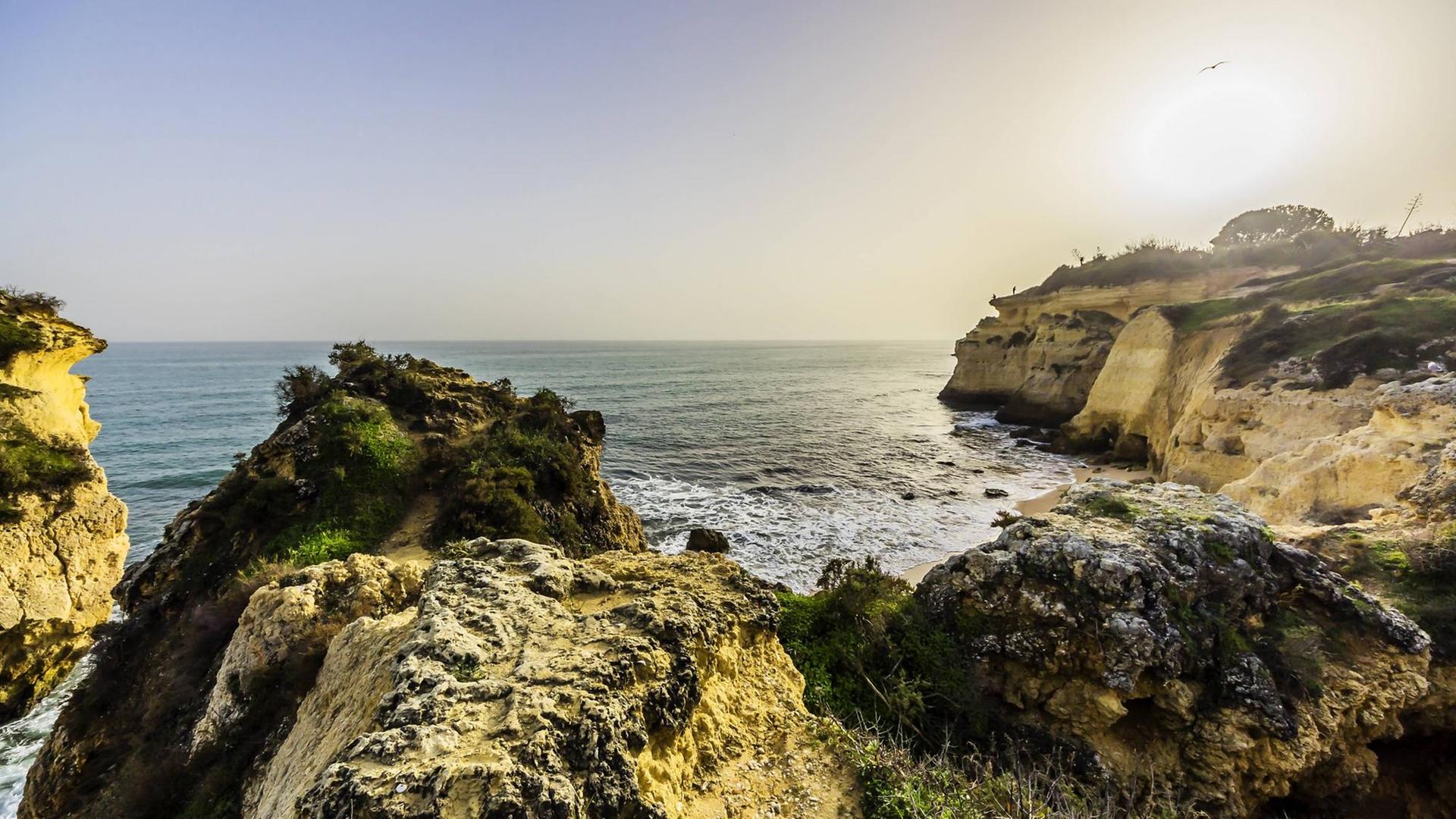 Ein Farbfoto von einer Felsküste am Meer im Sonnenuntergang in Portugal an der Algarve-Küste Ein Farbfoto von einer Felsküste am Meer im Sonnenuntergang in Portugal an der Algarve-Küste
