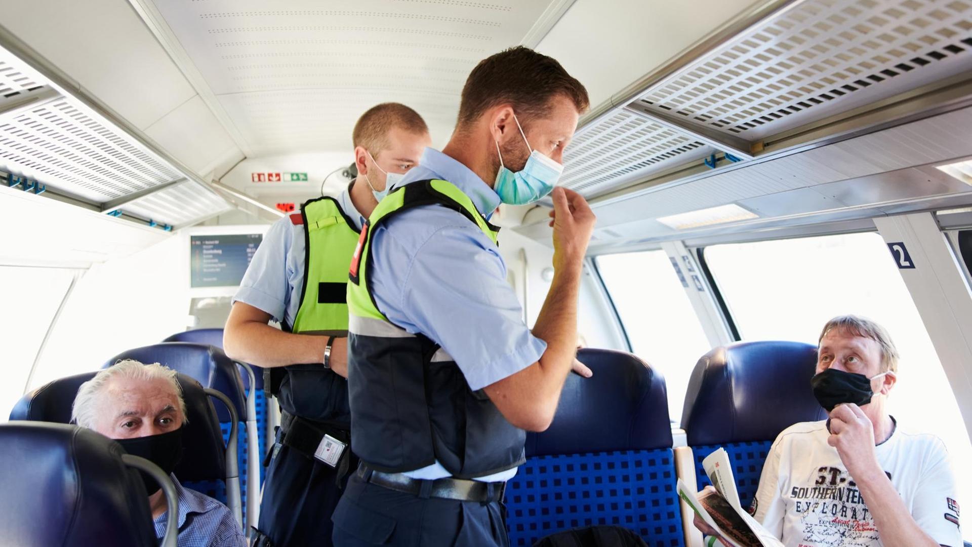 Mitarbeiter der DB Sicherheit und Beamte der Bundespolizei gehen durch einen Zug Richtung Neustrelitz und kontrollieren, ob die coronabedingte Maskenpflicht eingehalten wird.