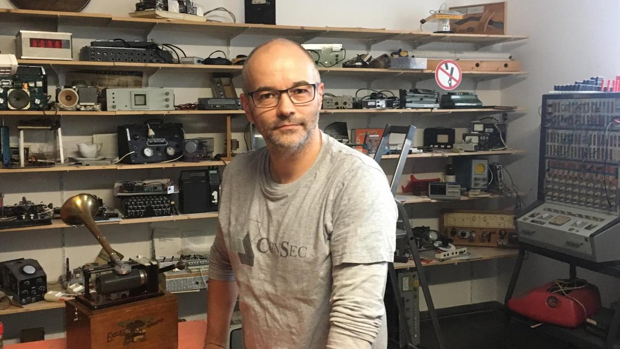 Porträt von Stefan Höltgen im Medienarchäologischen Fundus der Humboldt-Universität. Hinter ihm Grammophone, alte Kassetten-Recorder, Videokameras, Uhren, Radios, Kameras und anderes Inventar. Porträt von Stefan Höltgen im Medienarchäologischen Fundus der Humboldt-Universität. Hinter ihm Grammophone, alte Kassetten-Recorder, Videokameras, Uhren, Radios, Kameras und anderes Inventar.