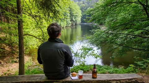 Ein Wanderer sitzt am Amselsee im Nationalpark Sächsische Schweiz.
