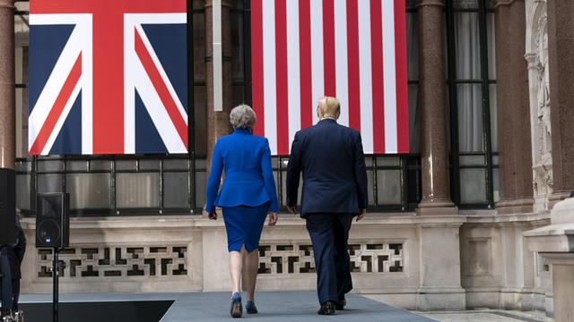 Das Bild zeigt die die scheidende britische Premierministerin Theresa May und US-Präsident Donald Trump auf dem Weg zu einer Pressekonferenz. Beide sind von hinten zu sehen.