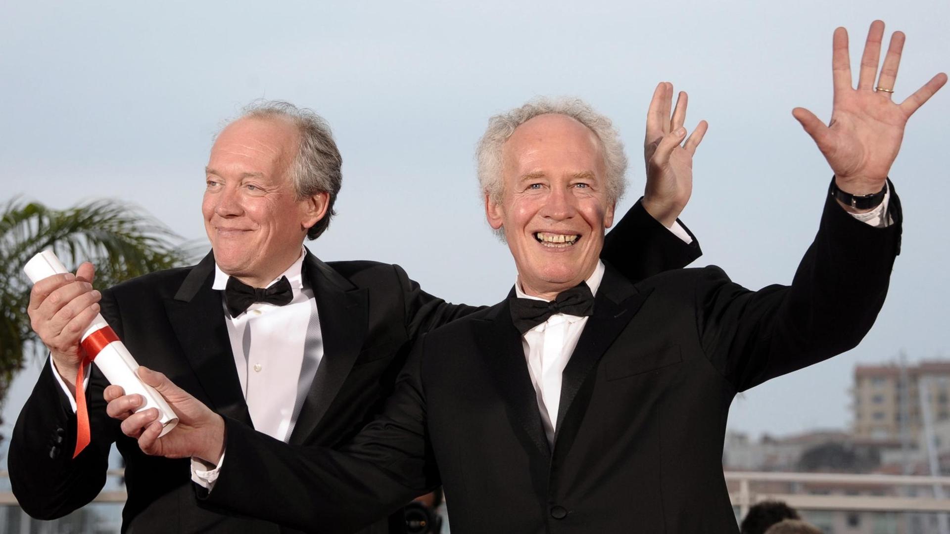 Die beiden belgischen Regie-Brüder Luc Dardenne (l) und Jean-Pierre Dardenne 2011 in Cannes: Sie winken in die Kamera.
