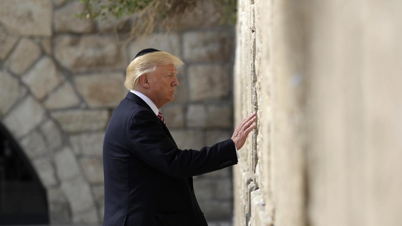 Trump trägt eine Kippa und berührt mit einer Hand die Klagemauer.