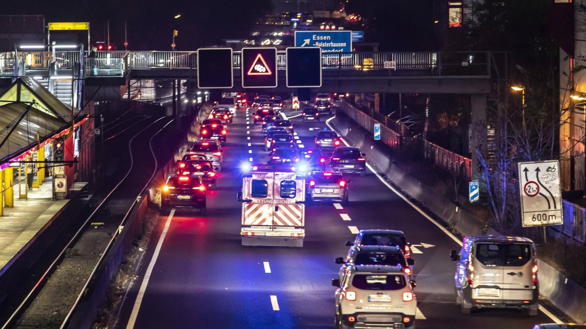 Ein Rettungswagen fährt mit Blaulicht auf der Autobahn A40 in Essen, durch eine gebildete Rettungsgasse.