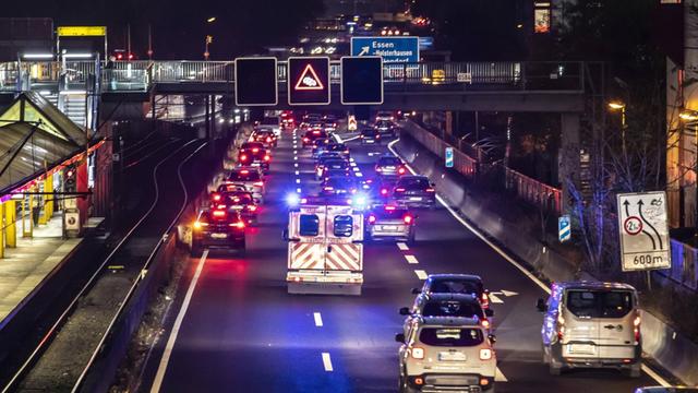 Ein Rettungswagen fährt mit Blaulicht auf der Autobahn A40 in Essen, durch eine gebildete Rettungsgasse.