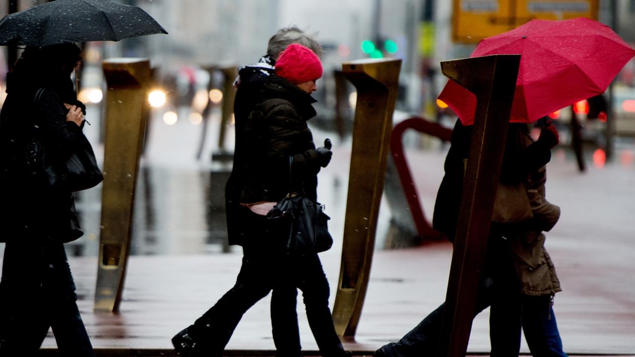 Passanten schützen sich am 10.12.2014 am Potsdamer Platz in Berlin mit Schirmen vor dem Regen. Passanten schützen sich am 10.12.2014 am Potsdamer Platz in Berlin mit Schirmen vor dem Regen.