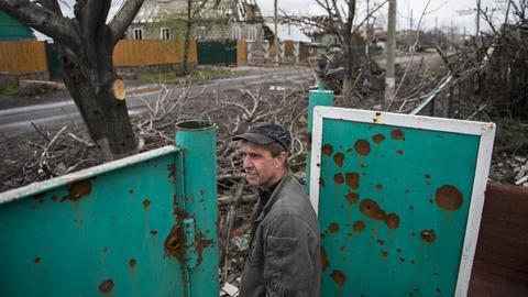 Ein Mann im Dorf Nikishino im Donbas schaut aus einer zerstörten Tür auf eine leere Dorfstraße.