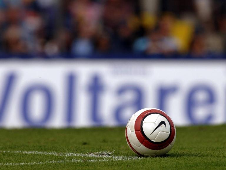 Ein Fußball liegt vor einer Werbebande des Schmerzmittel-Herstellers Voltaren