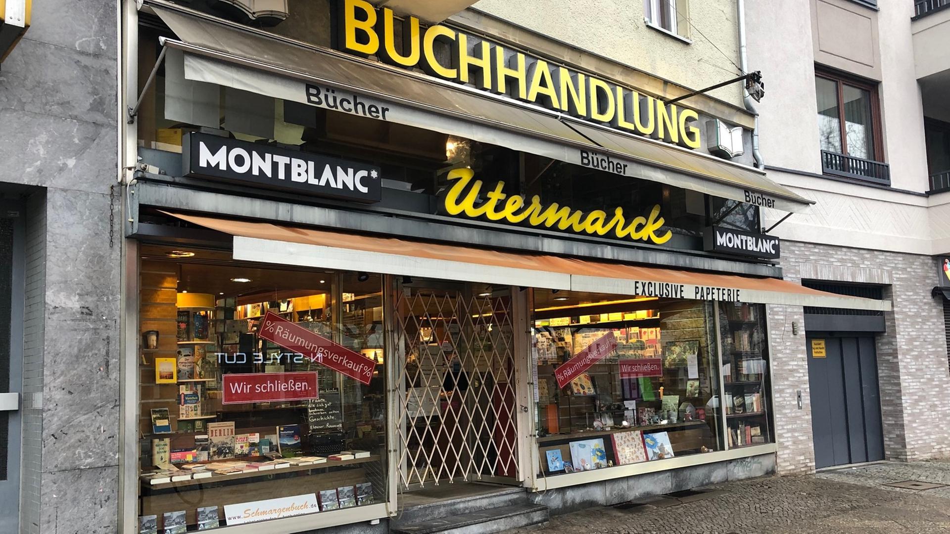 Buch- und Schreibwarengeschäft von außen. Am Schaufenster steht "Wir schließen". Buch- und Schreibwarengeschäft von außen. Am Schaufenster steht "Wir schließen".