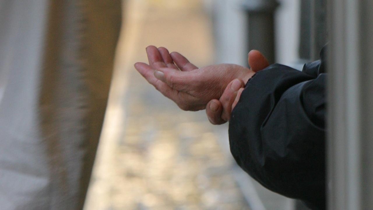 Eine Bettlerin streckt in der Innenstadt von Frankfurt am Main einem Passanten ihre Hand entgegen.