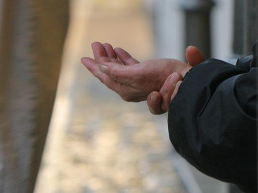 Eine Bettlerin streckt in der Innenstadt von Frankfurt am Main einem Passanten ihre Hand entgegen.