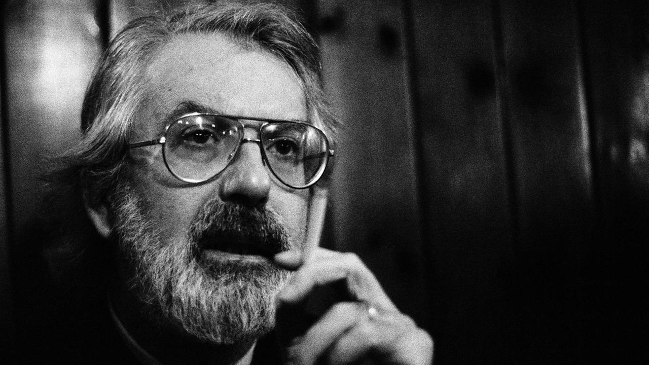 Der Schriftsteller Michael Ende 1990. Zu sehen ist ein Mann mit grauen Haaren, Bart und Brille, der eine Zigarette in der Hand hält. Der Schriftsteller Michael Ende 1990. Zu sehen ist ein Mann mit grauen Haaren, Bart und Brille, der eine Zigarette in der Hand hält.