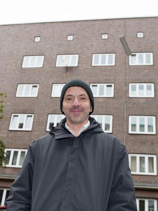Künstler Boran Burchhardt blickt am 03.11.2016 in Hamburg in die Kamera. Der Künstler möchte die Hauswand des Gebäudes hinter ihm vergolden, das Projekt sorgt im sozial schwachen Stadtteil Veddel für harsche Kritik.