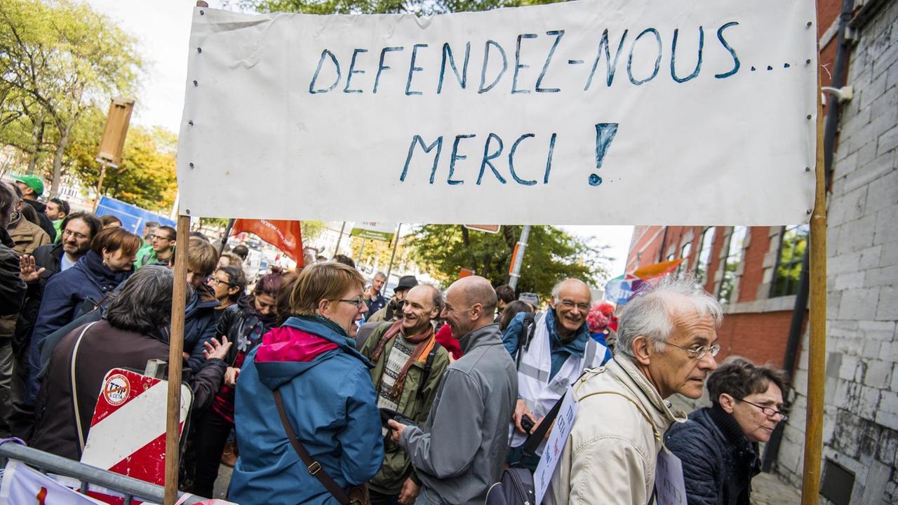 Das Bild zeigt viele Demonstranten sowie ein Transparent mit der Aufschrift "Defendez-Nous... Merci!" Das Bild zeigt viele Demonstranten sowie ein Transparent mit der Aufschrift "Defendez-Nous... Merci!"