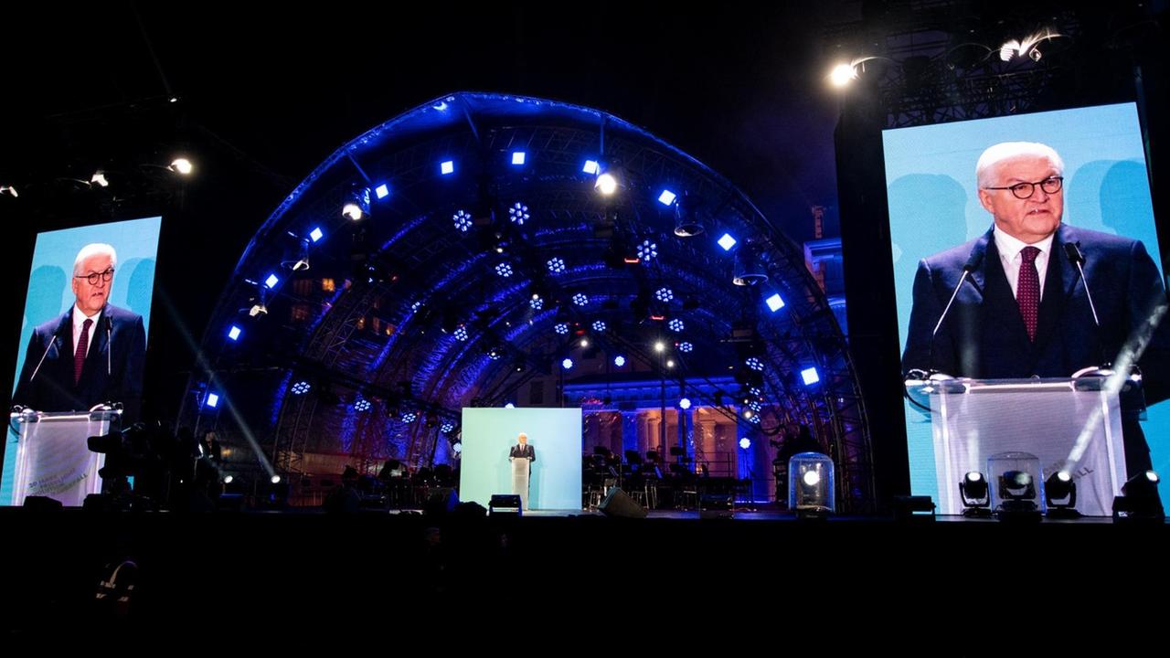 Steinmeier spricht Abends auf der beleuchteten Bühne. Sein Gesicht wird auch auf großen Leinwänden gezeigt. 