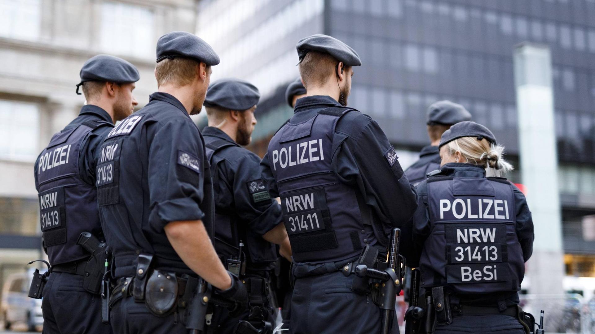Eine Gruppe von Polizistinnen und Polizisten - im Hintergrund sind Gebäude zu sehen. Eine Gruppe von Polizistinnen und Polizisten - im Hintergrund sind Gebäude zu sehen.