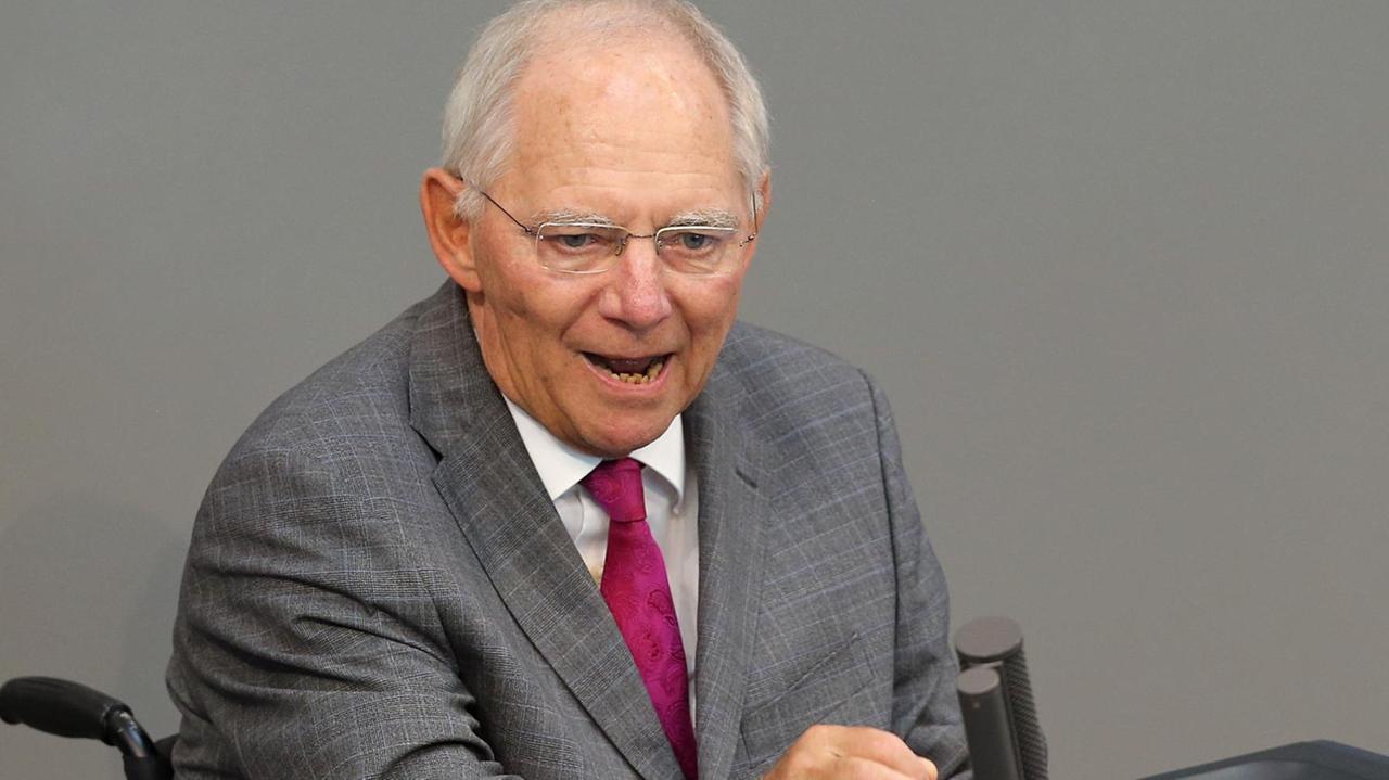Schäuble sitzt im Rollstuhl am Rednerpult und spricht. Er gestikuliert dabei mit der rechten Hand. Schäuble sitzt im Rollstuhl am Rednerpult und spricht. Er gestikuliert dabei mit der rechten Hand.