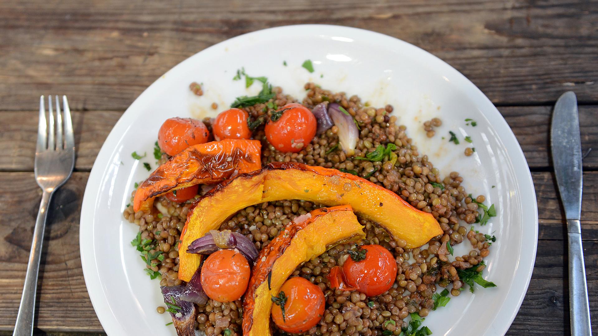 Veganes Essen aus Linsen, Kürbis, Zwiebeln und Tomaten auf einem Teller Veganes Essen aus Linsen, Kürbis, Zwiebeln und Tomaten auf einem Teller
