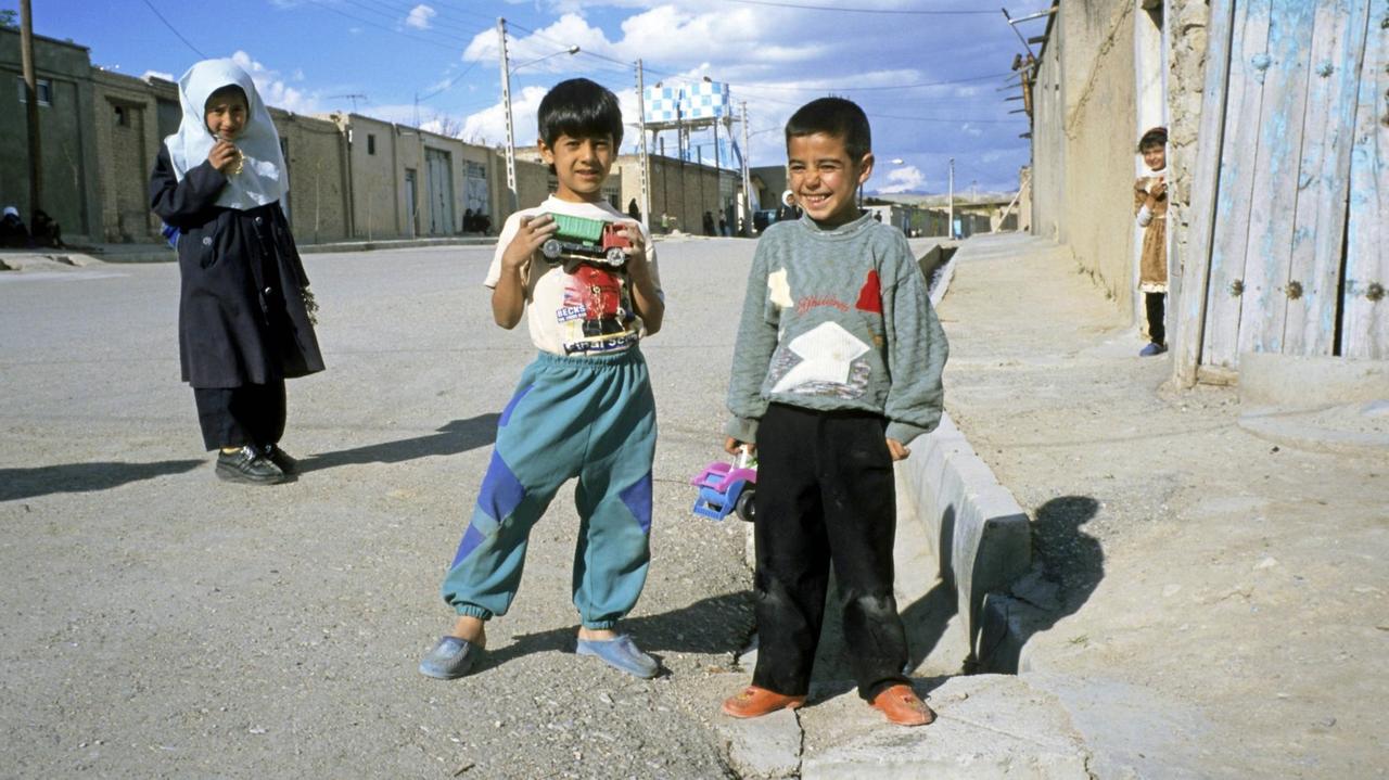 Vier Kinder stehen in einer Straße, in den Händen Spielzeuglastwagen. Sie strahlen den Fotografen an. Vier Kinder stehen in einer Straße, in den Händen Spielzeuglastwagen. Sie strahlen den Fotografen an.