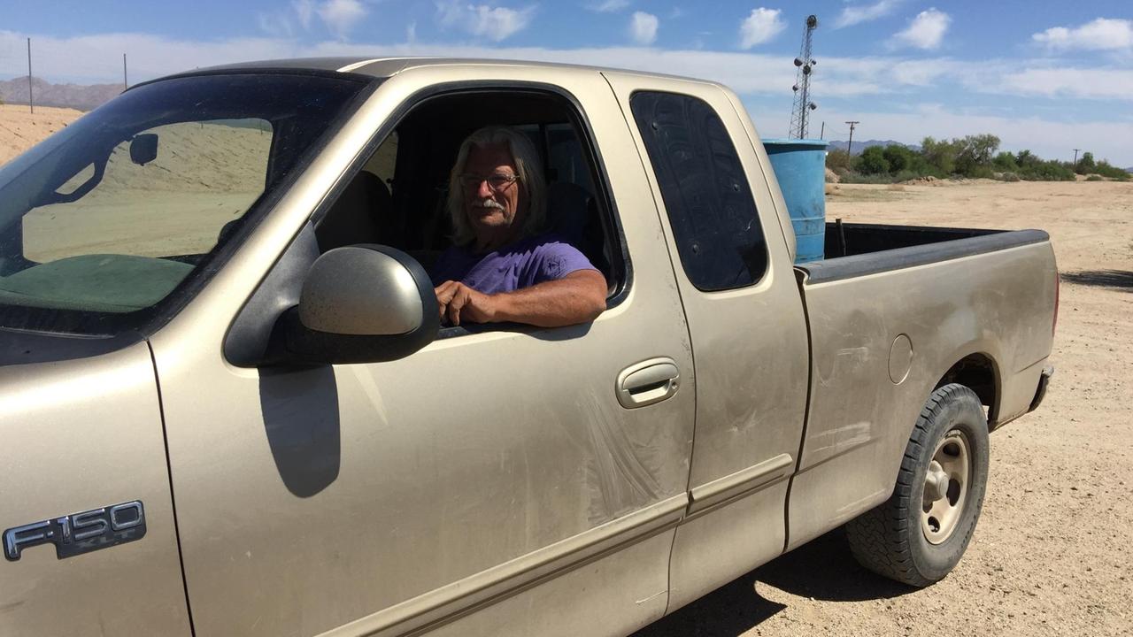 Bill Ammon sitzt in seinem große Auto mit Ladefläche in einer Wüste in den USA