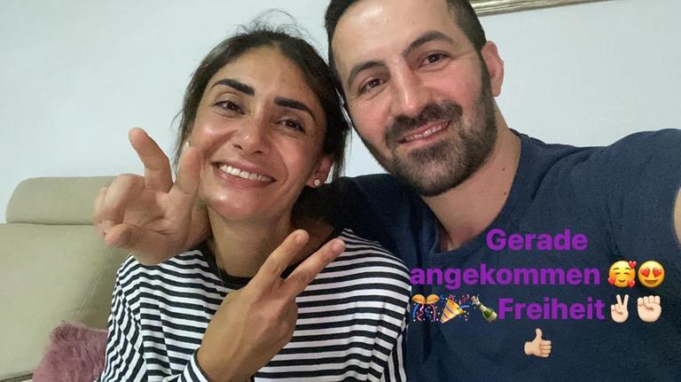 Ein Mann und eine Frau sitzen auf einem Sofa eng aneinander und machen mit ihrer rechten Hand das Siegeszeichen. Ein Mann und eine Frau sitzen auf einem Sofa eng aneinander und machen mit ihrer rechten Hand das Siegeszeichen.