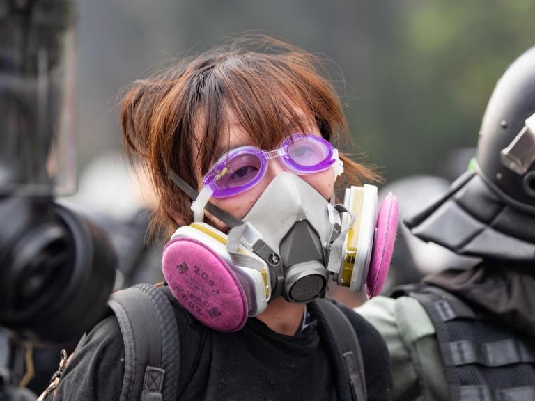 Eine protestierende Studentin, die eine Gasmaske trägt, wird von Polizisten verhaftet.