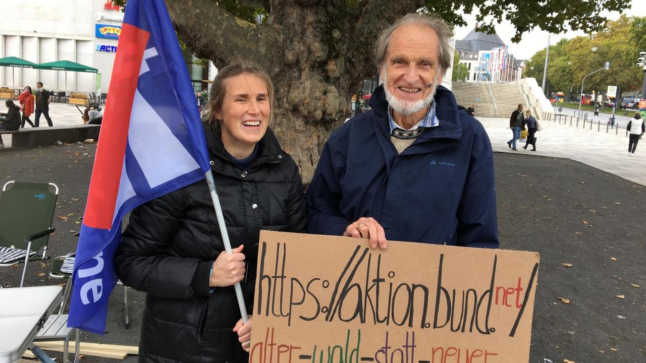 Angelika und Reinhard Forst stehen nebeneinander, sie hält eine Fahne, auf der die A 49 durchgestrichen ist, er ein Pappschild mit der Internetadresse ihrer Aktionsgemeinschaft.
