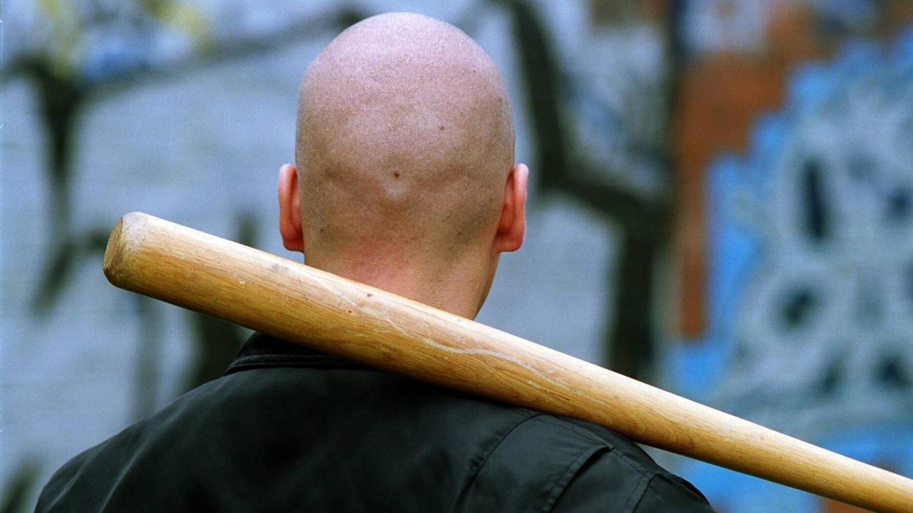 Ein kahlgeschoren Hinterkopf, auf dem Nacken ist ein Baseballschläger gehalten. Ein kahlgeschoren Hinterkopf, auf dem Nacken ist ein Baseballschläger gehalten.