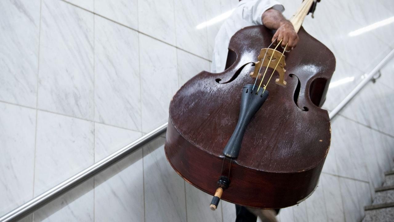 Ein Musiker trägt seinen Kontrabass eine Treppe hinauf Ein Musiker trägt seinen Kontrabass eine Treppe hinauf
