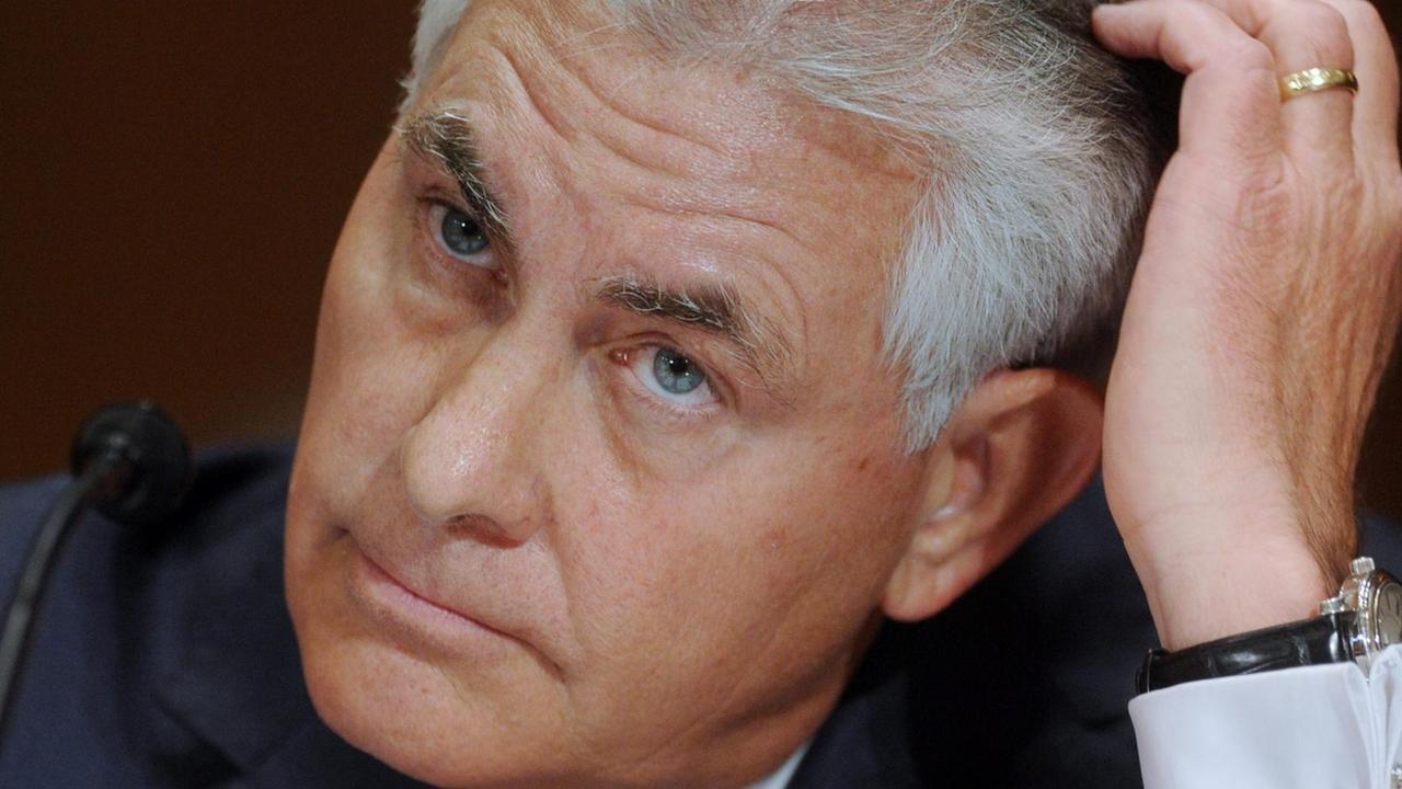 Nahaufnahme von Tillersons Gesicht, der sich vor einem Mikrofon mit ernstem Blick durch die Haare fährt. Nahaufnahme von Tillersons Gesicht, der sich vor einem Mikrofon mit ernstem Blick durch die Haare fährt.