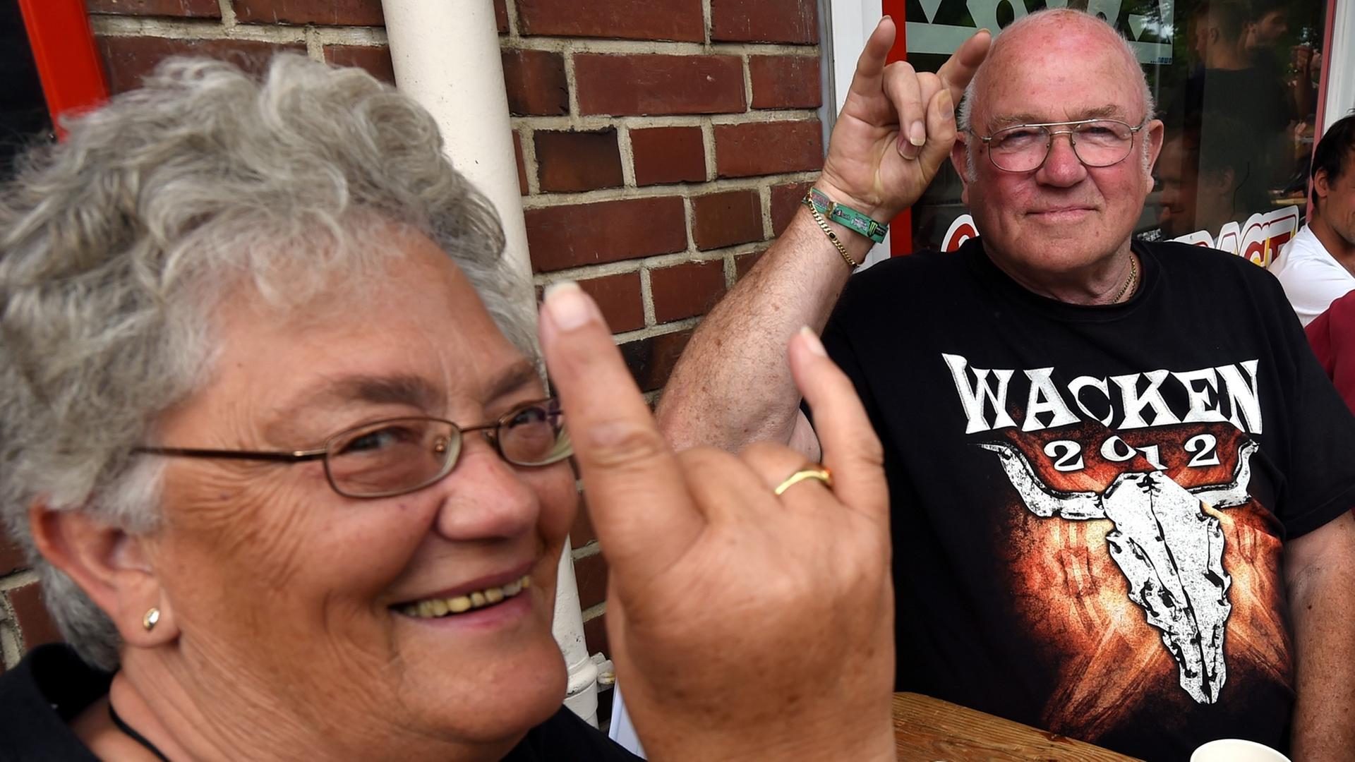 Die Anwohner Gerda und Karl-Heinz begrüssen in Wacken die anreisenden Heavy-Metal-Fans mit dem "Pommesgabel-Zeichen".